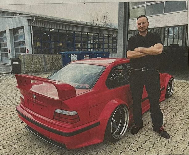 Christian Klein of Unlimited Auto stands with his custom widebody BMW E36 build in Weiden.