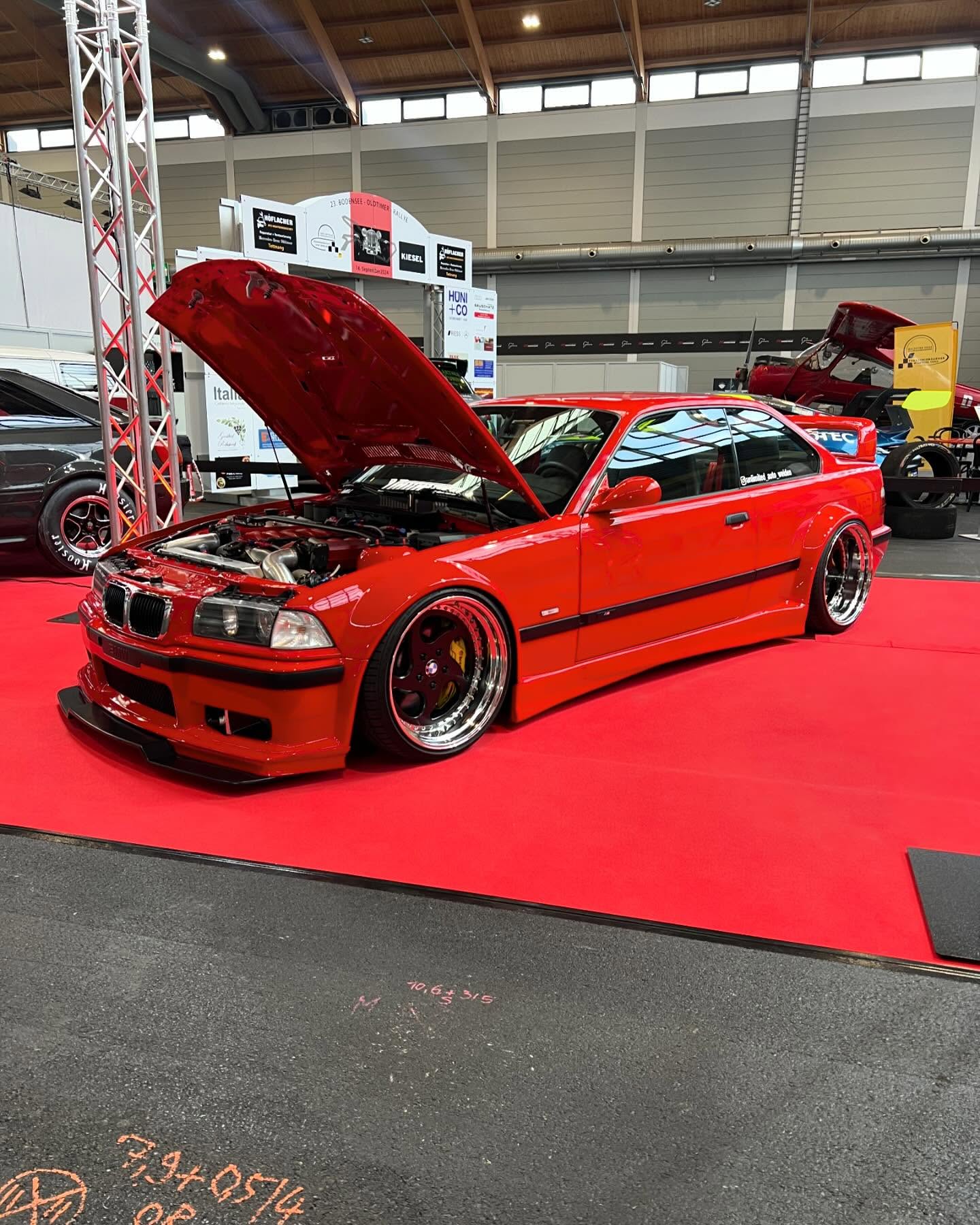 BMW E36 V12 BiTurbo mit 1012 PS von Unlimited Auto, Breitbau in Rot mit offener Haube auf Messestand